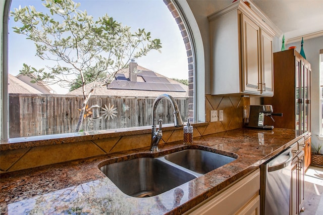 kitchen featuring a sink, dark stone countertops, a healthy amount of sunlight, backsplash, and dishwasher