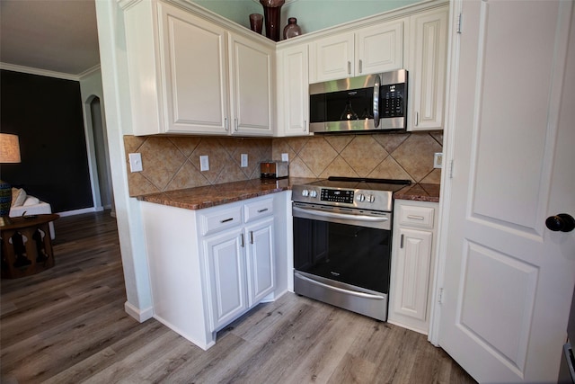 kitchen featuring tasteful backsplash, stainless steel appliances, light wood-style floors, ornamental molding, and baseboards