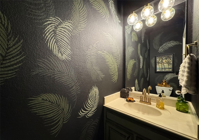 bathroom featuring toilet, a notable chandelier, and vanity