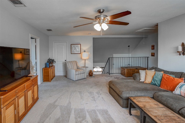 living area featuring attic access, visible vents, light colored carpet, and a ceiling fan