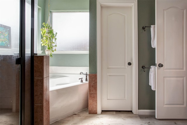 full bath with a bath and wood finished floors
