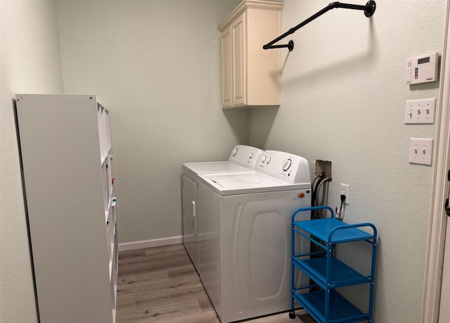 washroom with wood finished floors, washing machine and clothes dryer, cabinet space, and baseboards