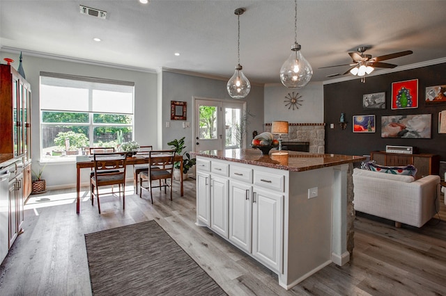 kitchen featuring visible vents, light wood-style flooring, ornamental molding, white cabinets, and open floor plan