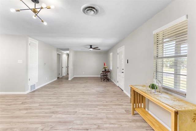interior space featuring light wood finished floors, visible vents, baseboards, and ceiling fan with notable chandelier