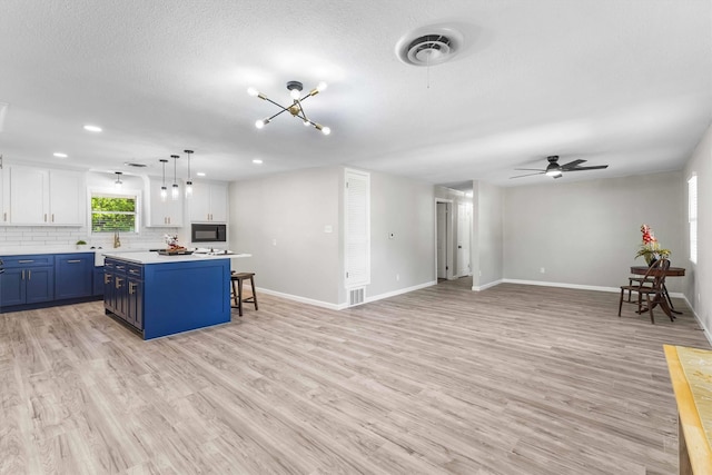 kitchen with white cabinets, visible vents, light countertops, blue cabinets, and a center island
