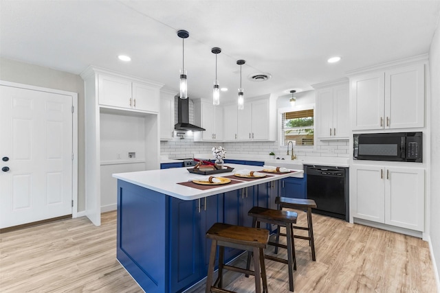 kitchen with tasteful backsplash, light countertops, wall chimney range hood, white cabinets, and black appliances