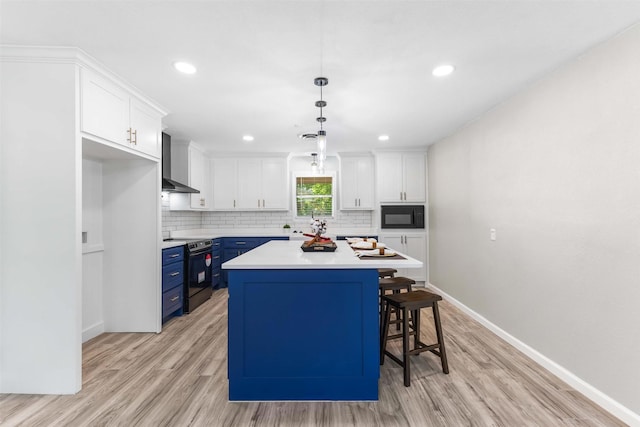 kitchen with black appliances, blue cabinets, white cabinets, and wall chimney exhaust hood