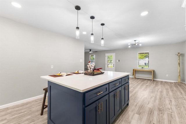kitchen featuring light wood finished floors, recessed lighting, baseboards, a kitchen island, and light countertops