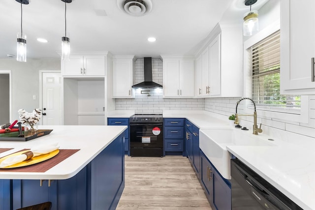 kitchen with wall chimney range hood, a sink, light countertops, blue cabinets, and black appliances