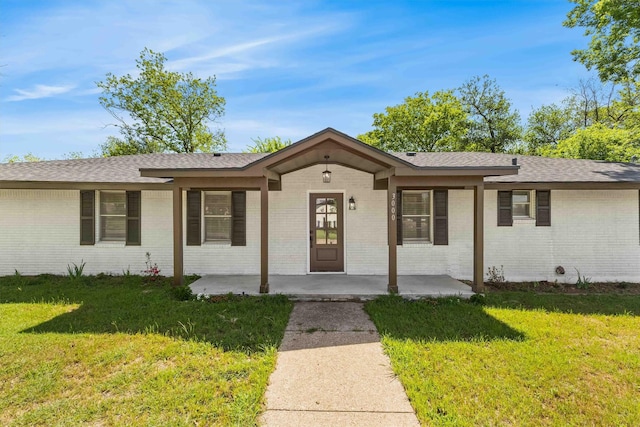 single story home featuring a front yard, a shingled roof, and brick siding