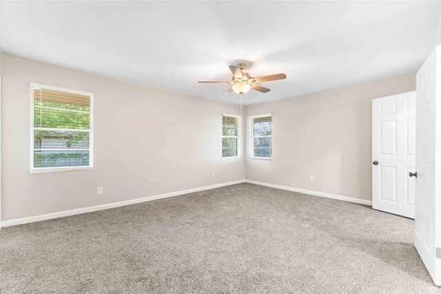 unfurnished room with a healthy amount of sunlight, ceiling fan, baseboards, and carpet floors