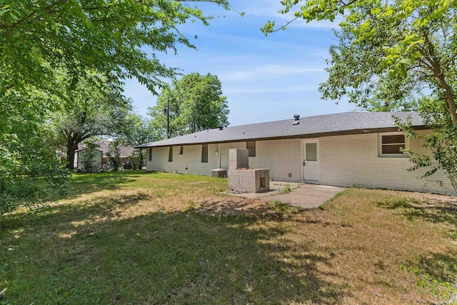 back of house featuring a patio, brick siding, central AC, and a yard