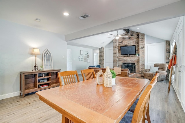 dining room with visible vents, a ceiling fan, light wood-type flooring, and a fireplace