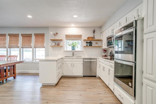 kitchen featuring tasteful backsplash, stainless steel appliances, open shelves, light countertops, and a sink