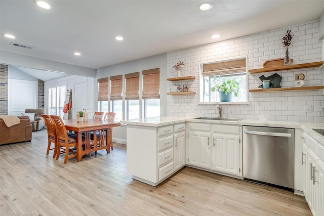kitchen featuring a sink, open shelves, visible vents, a peninsula, and dishwasher