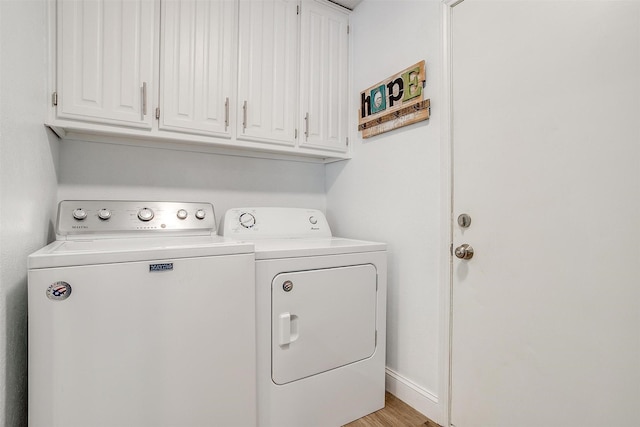 laundry area with light wood-style flooring, washing machine and clothes dryer, cabinet space, and baseboards