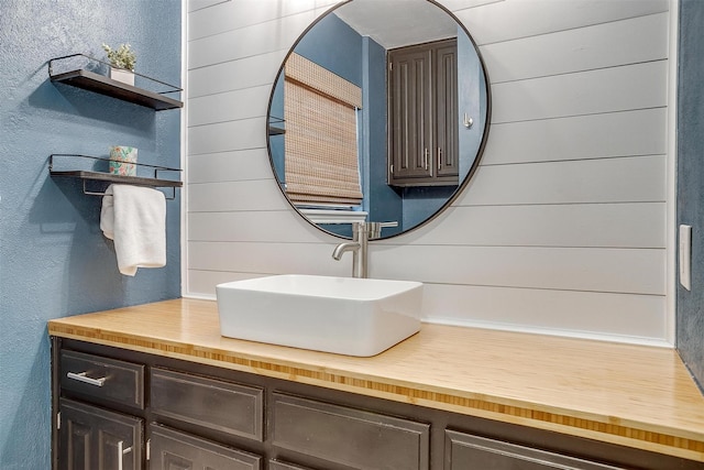 bathroom with wooden walls, a textured wall, and vanity