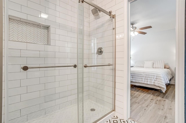 ensuite bathroom with wood finished floors, a shower stall, a ceiling fan, and ensuite bath