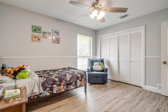 bedroom with a closet, ceiling fan, visible vents, light wood-style flooring, and baseboards