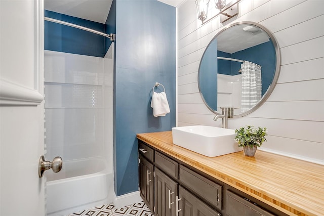 full bathroom with wooden walls, shower / bath combo, vanity, and baseboards