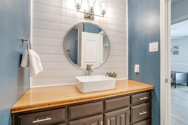 bathroom featuring wood walls, wood finished floors, and vanity