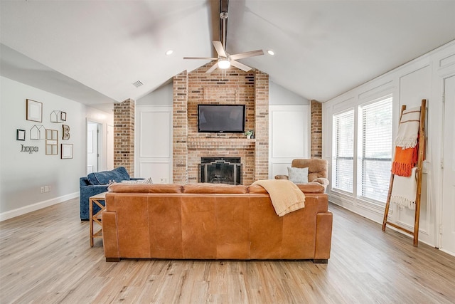 living room with light wood-style floors, ceiling fan, visible vents, a fireplace, and vaulted ceiling with beams