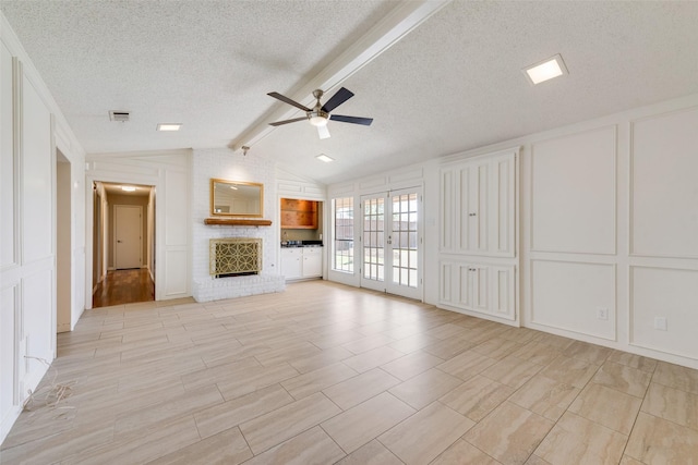 unfurnished living room featuring ceiling fan, vaulted ceiling with beams, visible vents, a decorative wall, and a textured ceiling