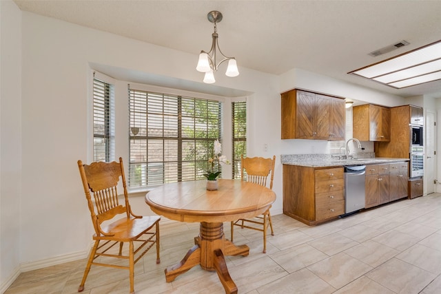 912 E Berkeley Dr, Richardson, TX 75081 - kitchen featuring brown cabinets, a sink, appliances with stainless steel finishes, decorative light fixtures, and baseboards