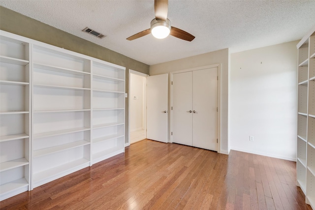 unfurnished bedroom with baseboards, visible vents, wood finished floors, and a textured ceiling