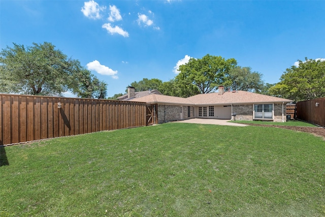 back of house featuring a yard, a patio area, brick siding, and a fenced backyard