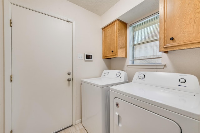 clothes washing area with separate washer and dryer, cabinet space, and a textured ceiling