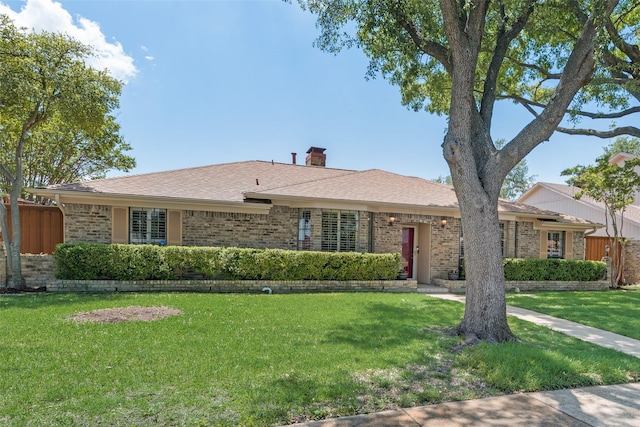 ranch-style house with fence, a chimney, a front yard, and brick siding