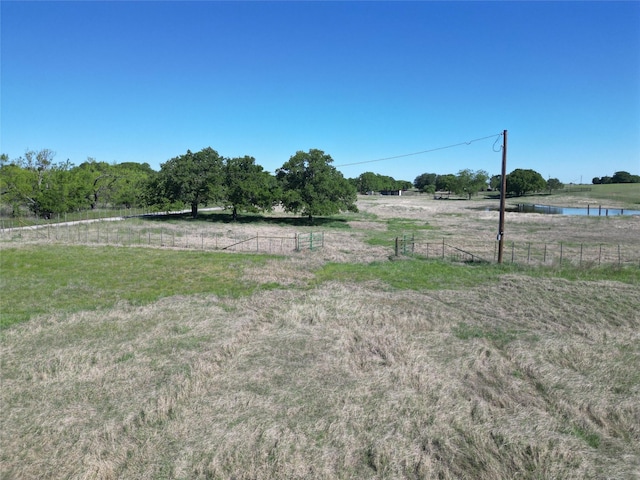 view of yard with fence and a rural view