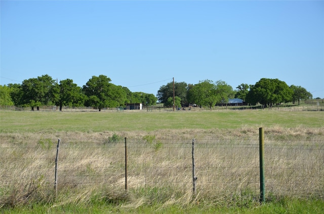 view of yard with fence and a rural view