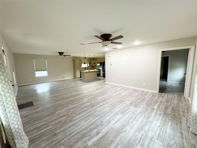 unfurnished living room featuring visible vents, light wood-type flooring, a ceiling fan, and baseboards