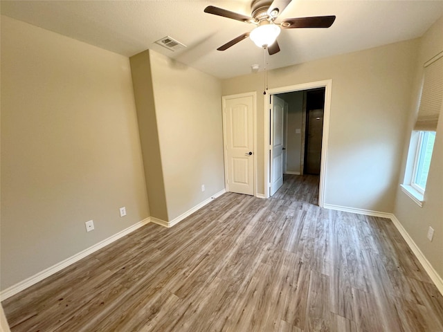 unfurnished bedroom featuring wood finished floors, a ceiling fan, visible vents, and baseboards