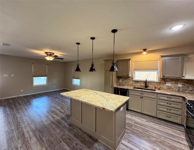 kitchen featuring a sink, decorative backsplash, gray cabinets, a ceiling fan, and visible vents