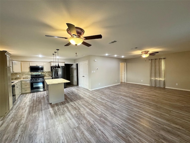 kitchen with appliances with stainless steel finishes, ceiling fan, a center island, visible vents, and open floor plan