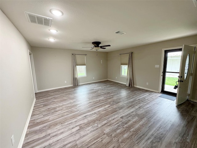 empty room featuring visible vents, wood finished floors, and plenty of natural light
