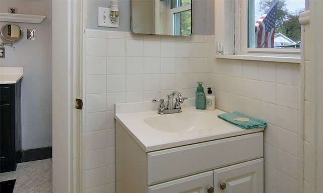 bathroom with a wealth of natural light, vanity, and tile walls