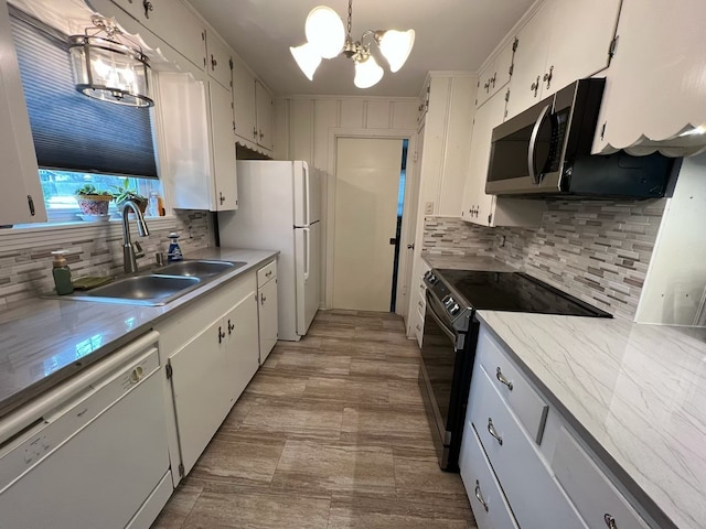 kitchen with a sink, light countertops, an inviting chandelier, white appliances, and backsplash