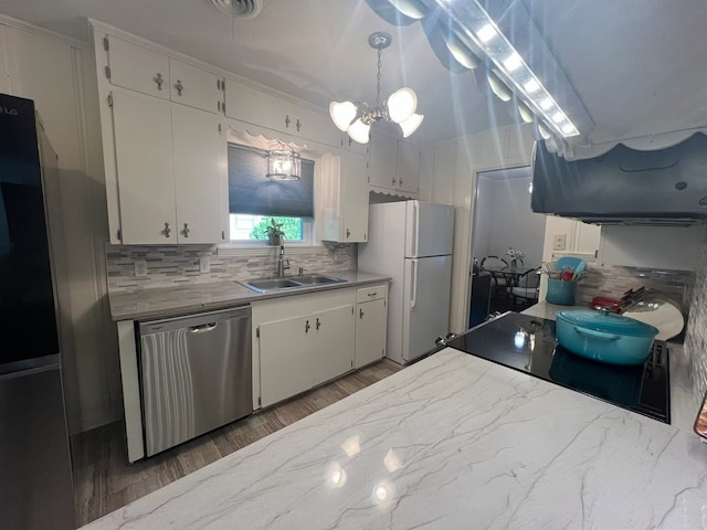 kitchen featuring stainless steel dishwasher, a sink, freestanding refrigerator, and tasteful backsplash