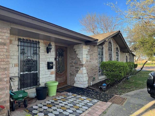 entrance to property with brick siding and a shingled roof