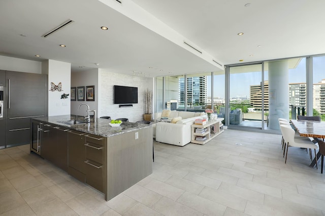 kitchen with dark stone countertops, an island with sink, modern cabinets, and a sink