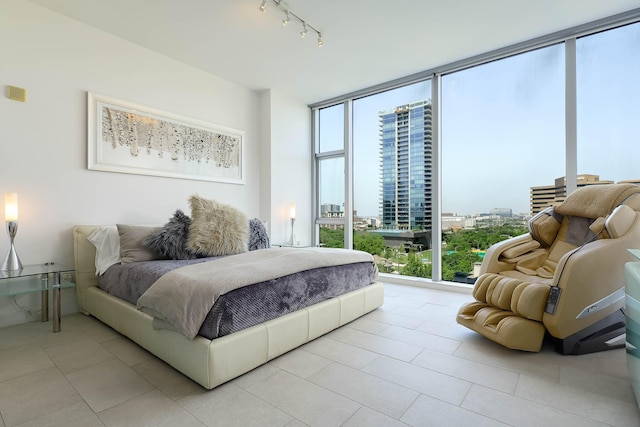 bedroom with track lighting, light tile patterned flooring, multiple windows, and floor to ceiling windows