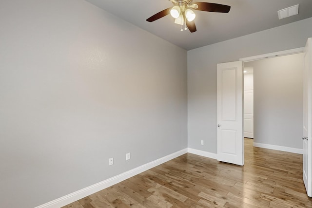 spare room with ceiling fan, visible vents, baseboards, and light wood finished floors