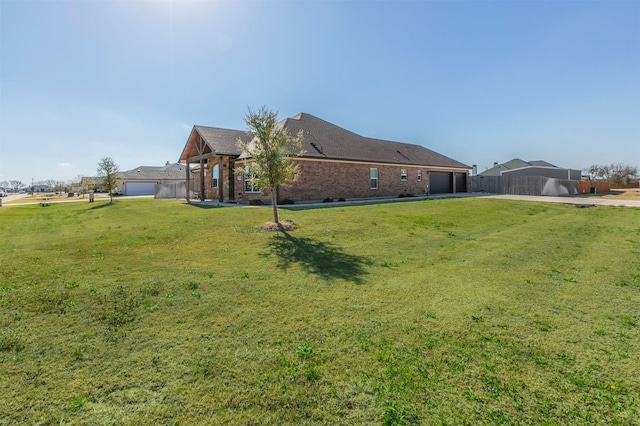 view of yard with a garage, fence, and driveway