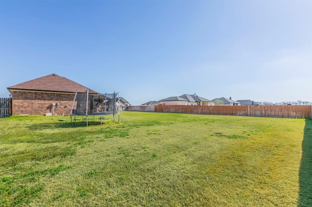 view of yard with a trampoline and a fenced backyard