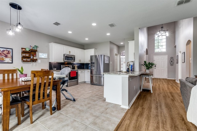 kitchen featuring a peninsula, visible vents, white cabinets, and appliances with stainless steel finishes