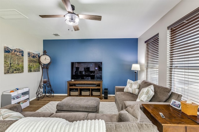 living area featuring baseboards, visible vents, wood finished floors, and a ceiling fan